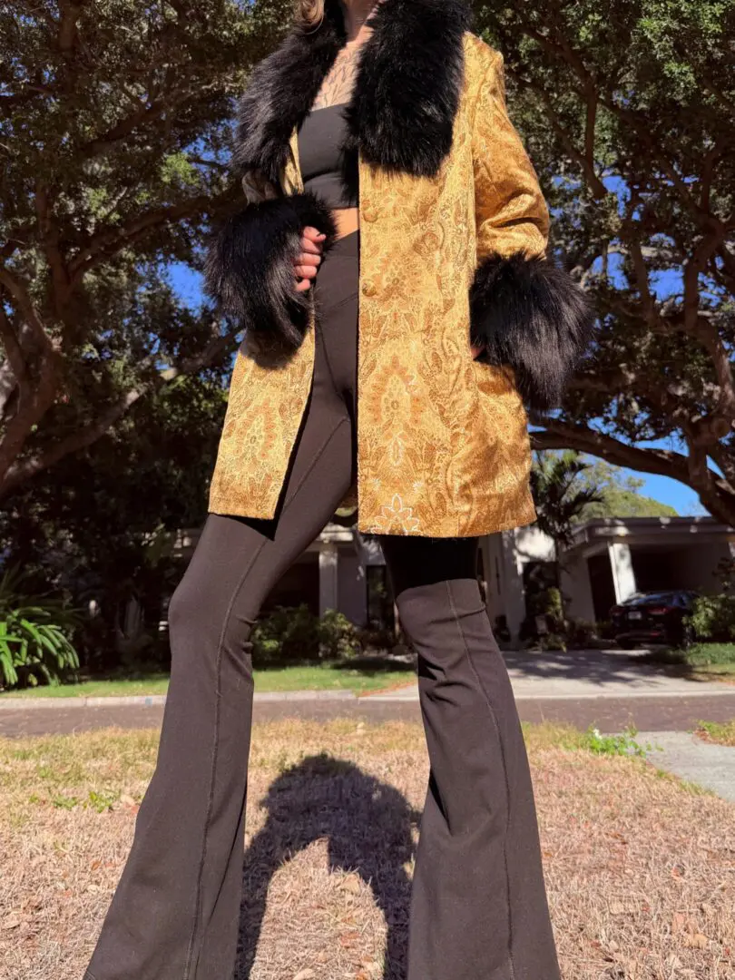 Person in gold fur-trimmed coat and flared pants