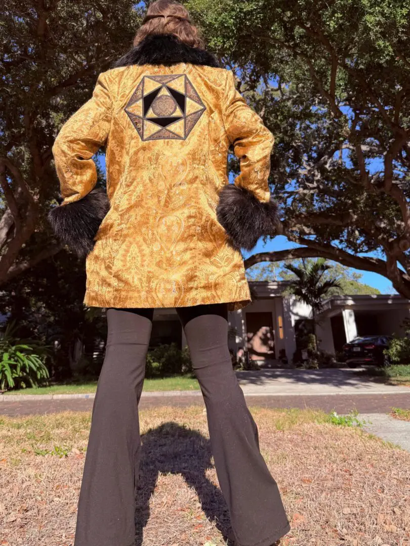 Person wearing gold patterned coat with geometric patch