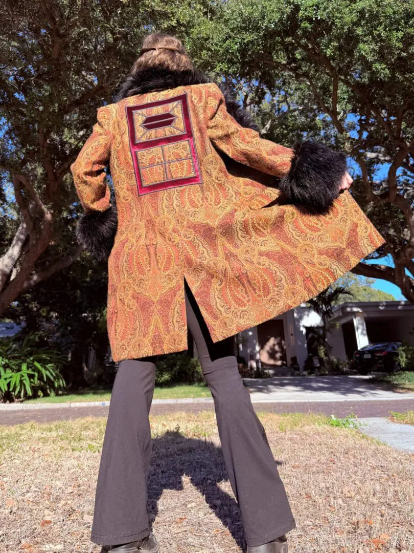 Person wearing paisley coat with fur cuffs