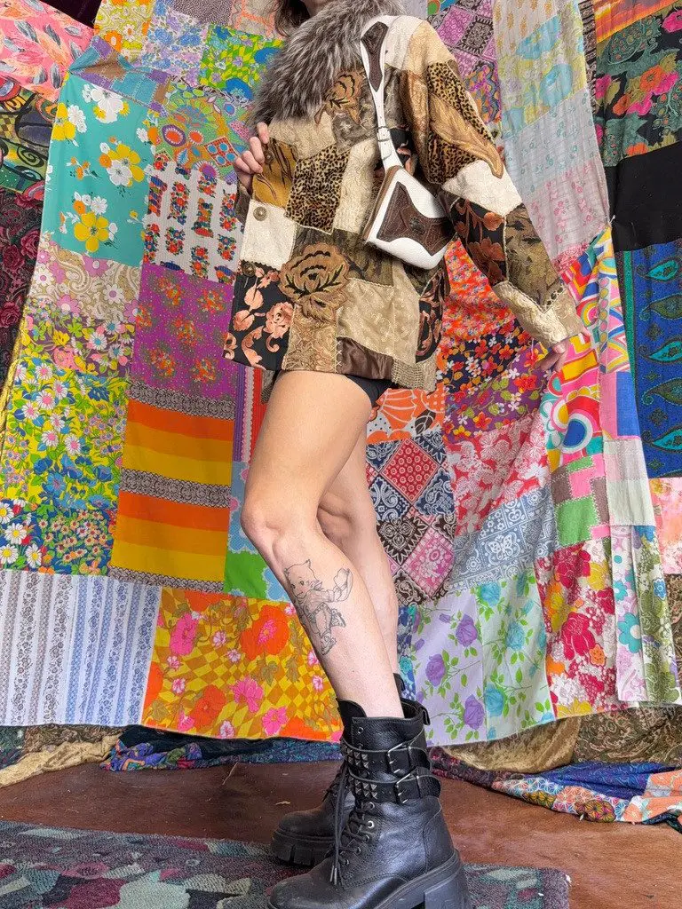 Person wearing patchwork jacket, boots, leg tattoo