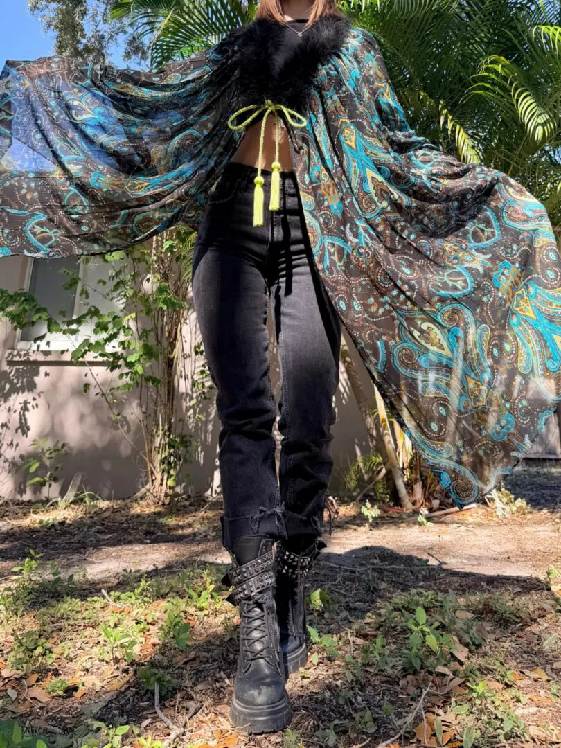 Person in flowing paisley cape, black combat boots