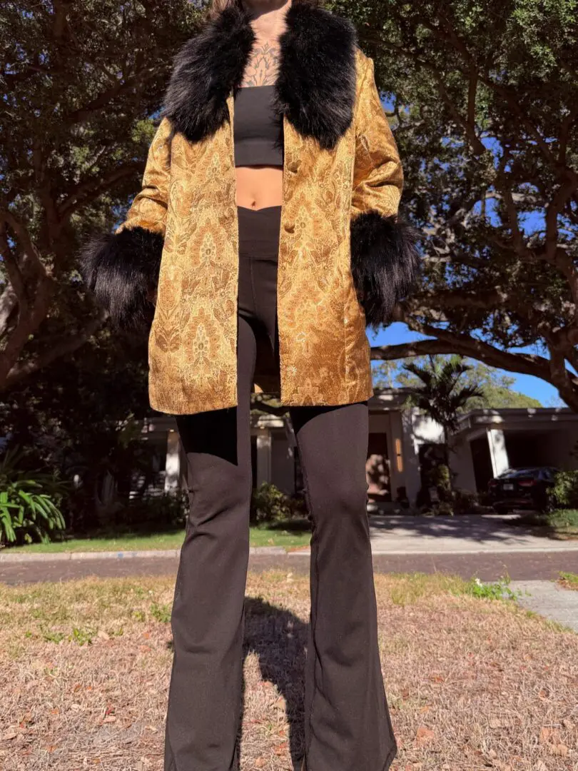 Person wearing gold brocade coat with black fur