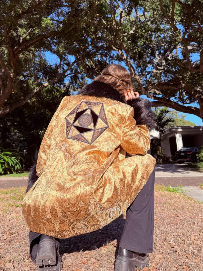 Crouching person in gold jacket with geometric patch
