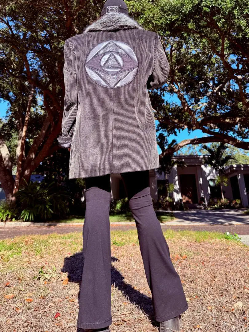 Person wearing embroidered coat with circular emblem