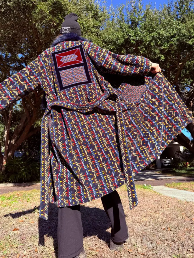 Person in colorful patterned robe with outstretched arms