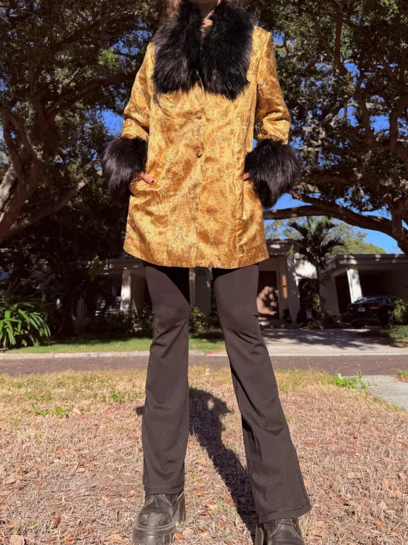 Person wearing gold brocade coat with fur