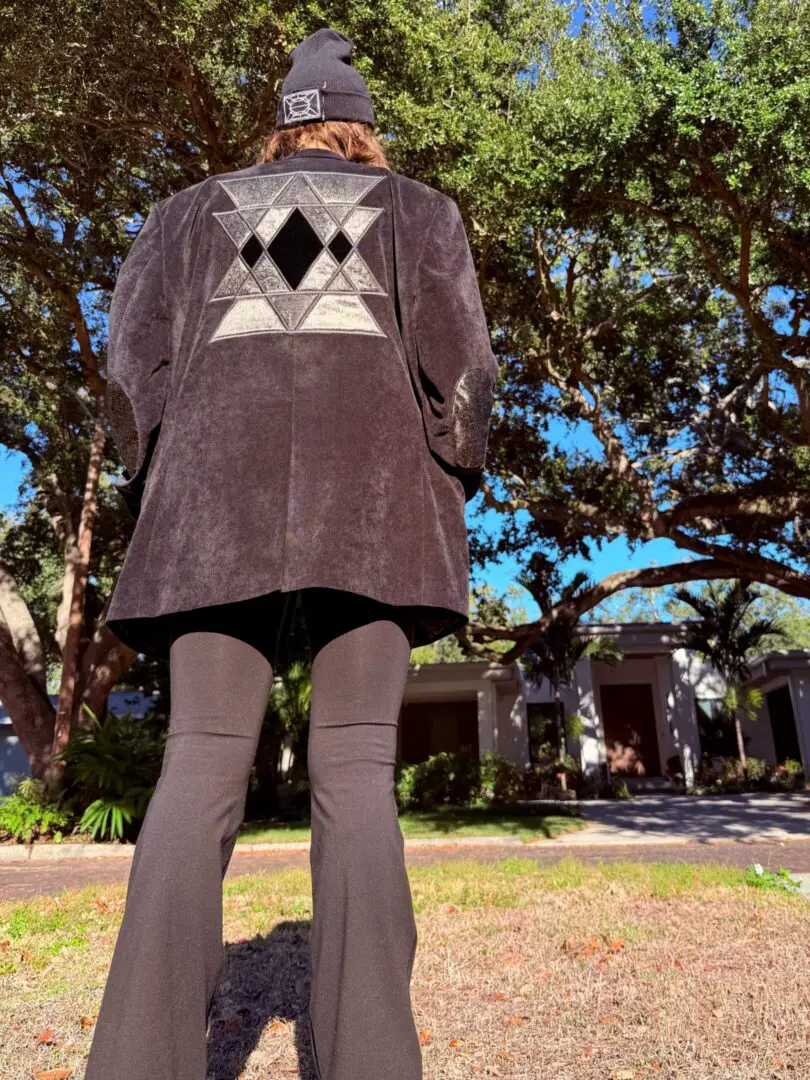 Person outdoors wearing black jacket with geometric design